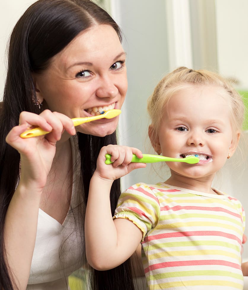 Mother and daughter brushing their teeth together