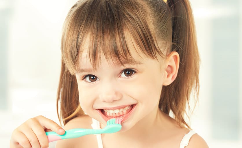Young girl with dental sealants brushing her teeth